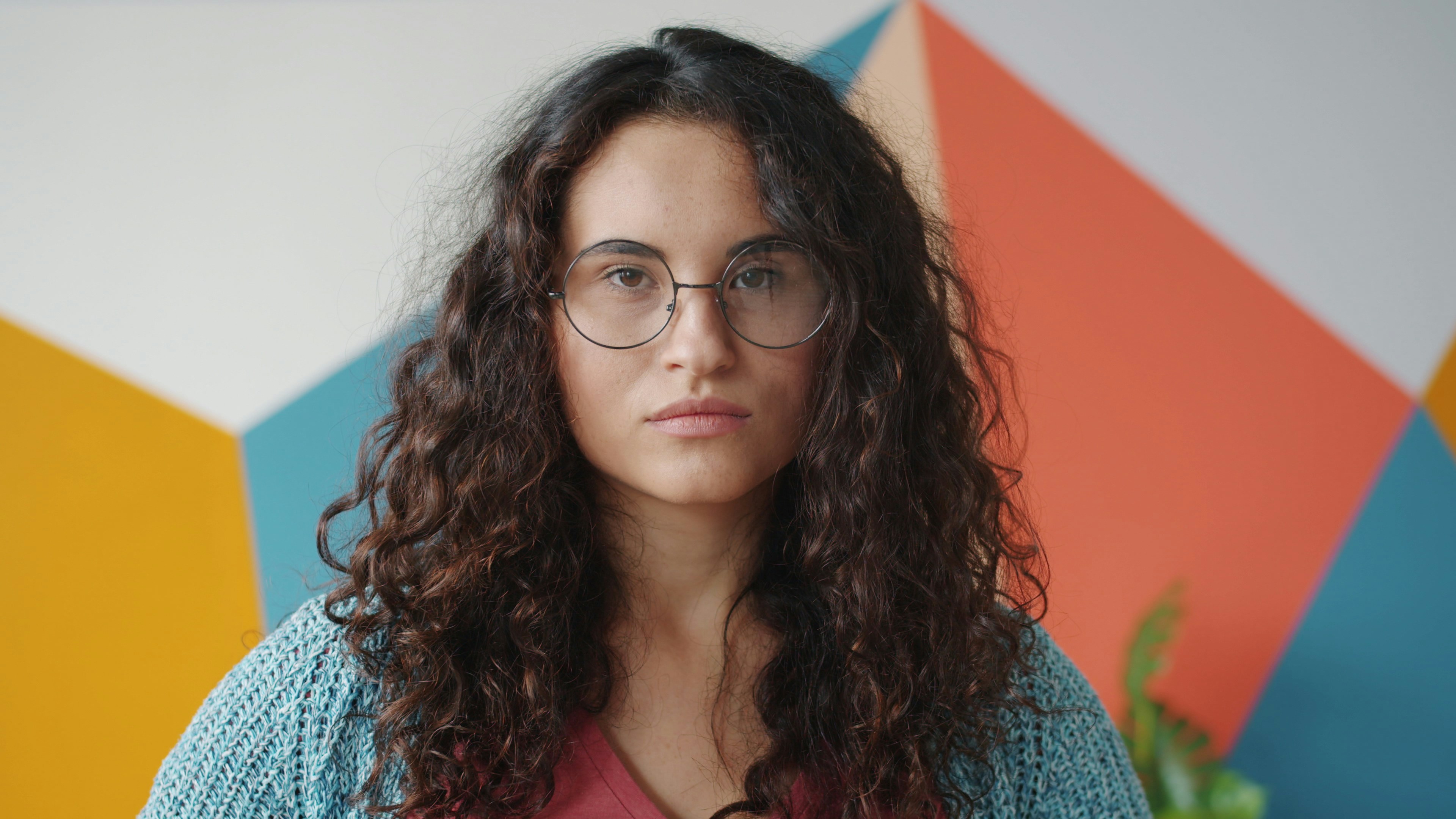 A woman with curly hair and glasses looking at the camera.