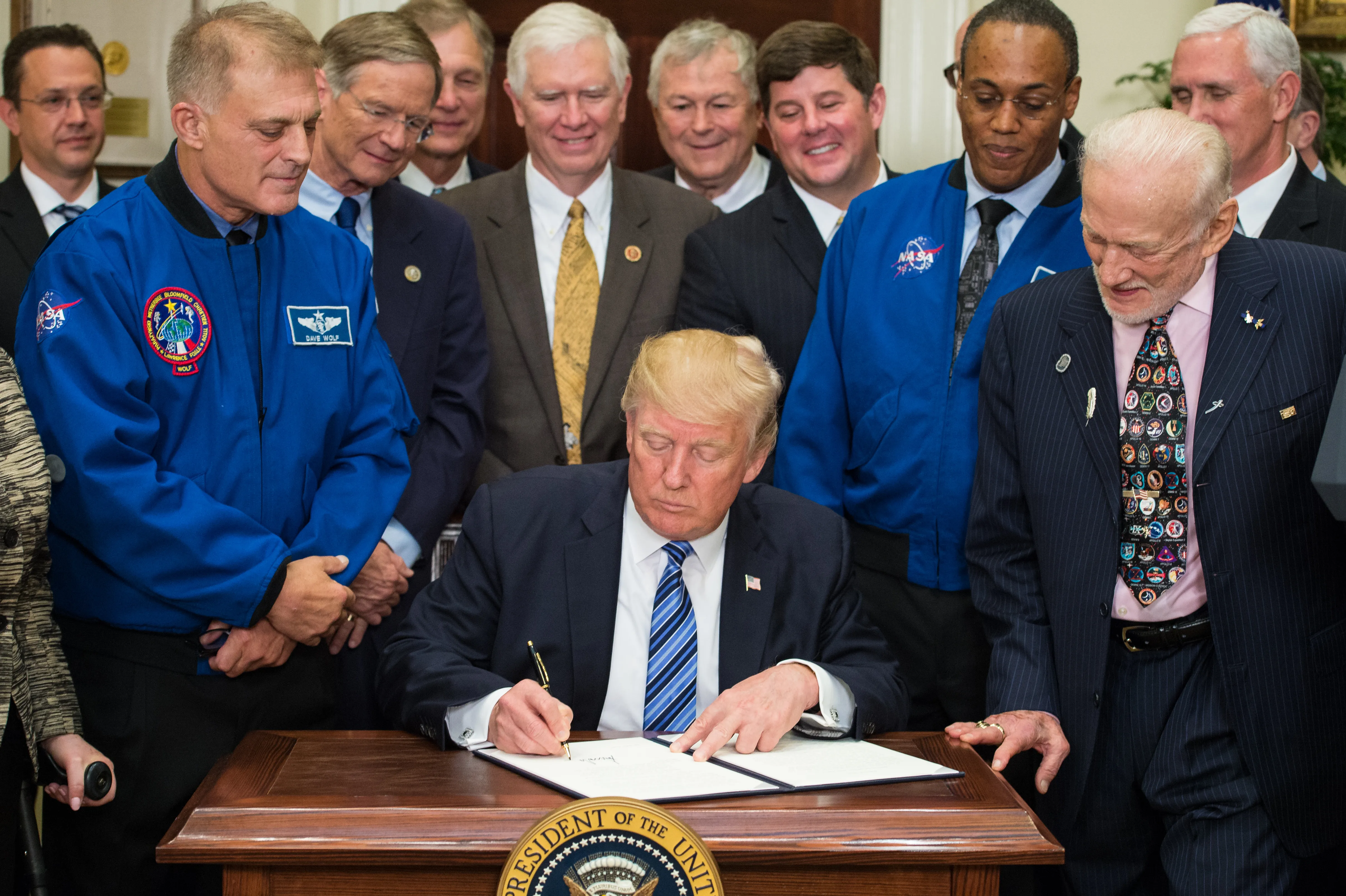 President Donald Trump signing a paper surrounded by the National Space Council.
